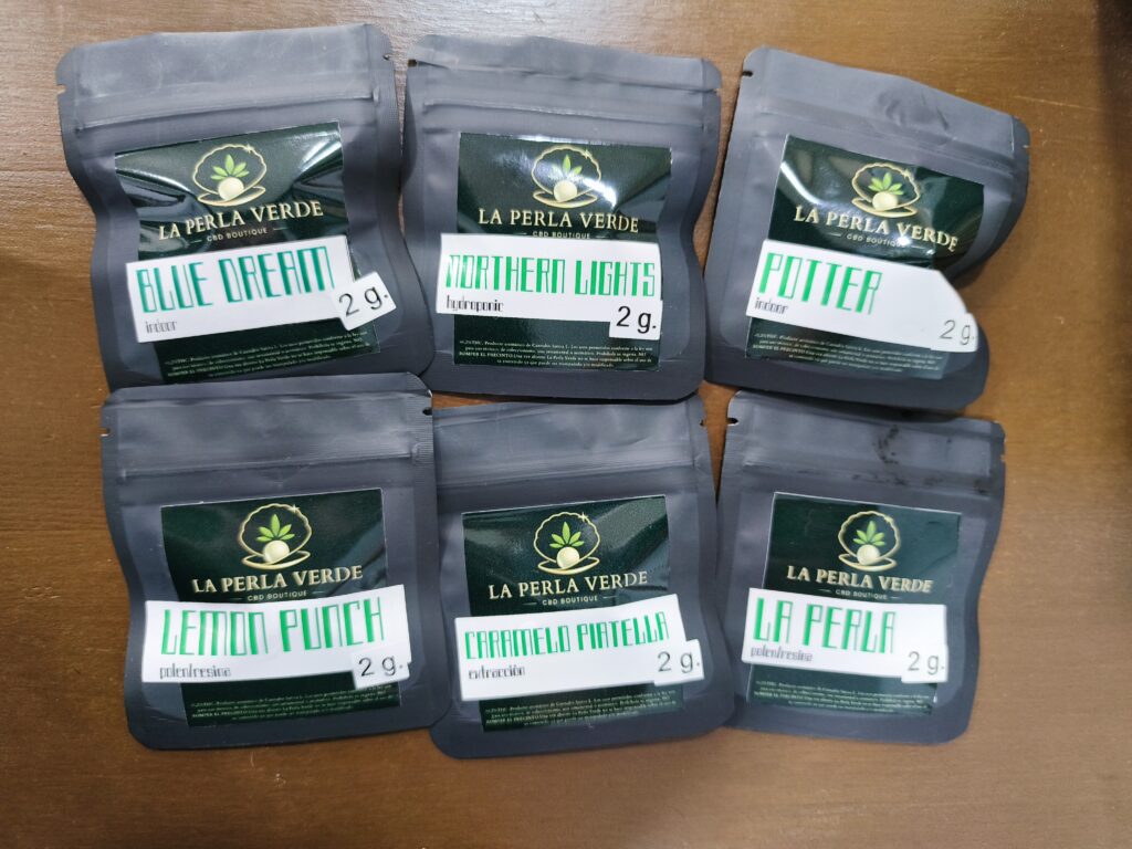 pack de 6 bolsas de flores de cbd de la perla verde cbd de 2 gramos cada una sobre un fondo de madera